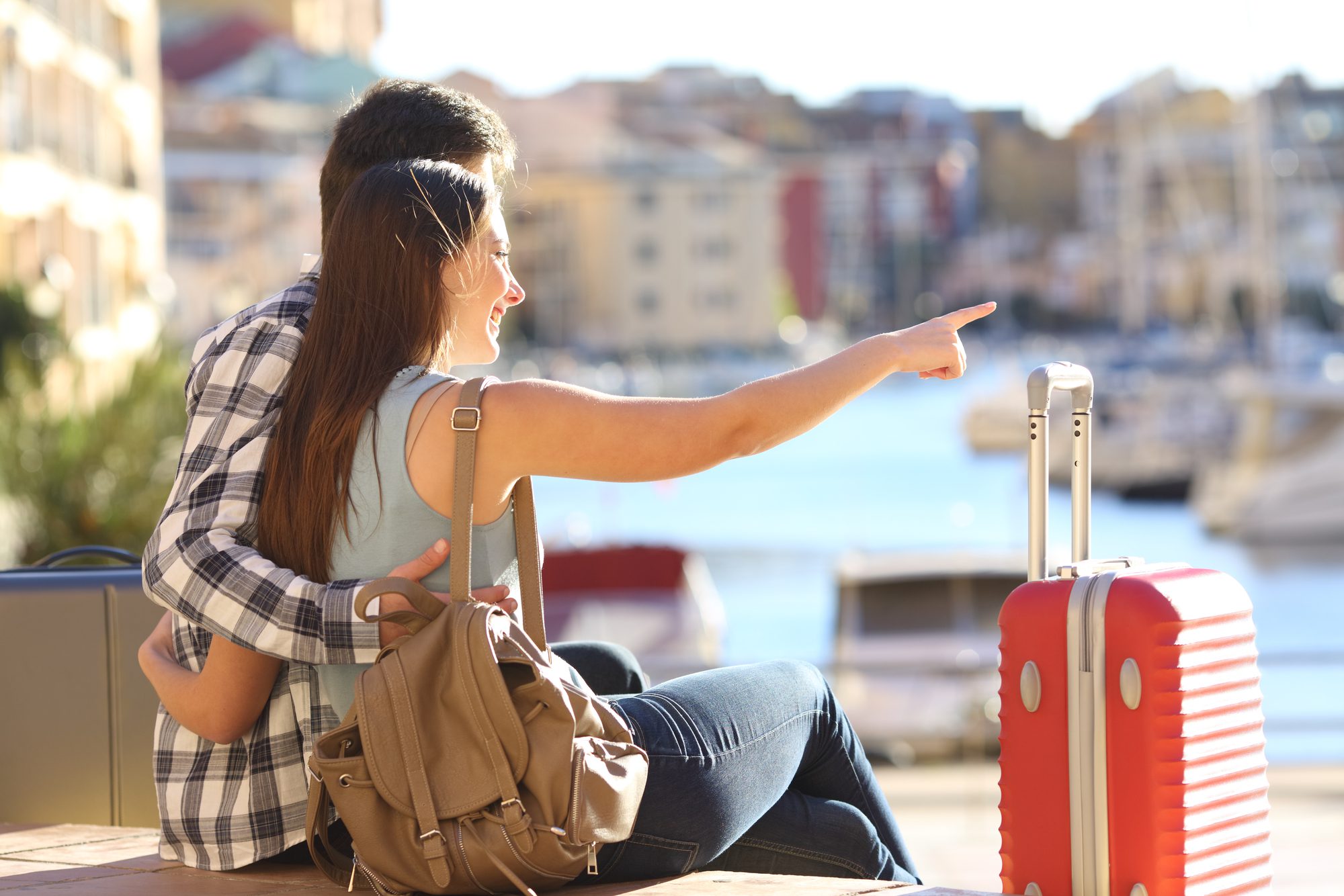 Portrait of couple of tourists with suitcases sitting