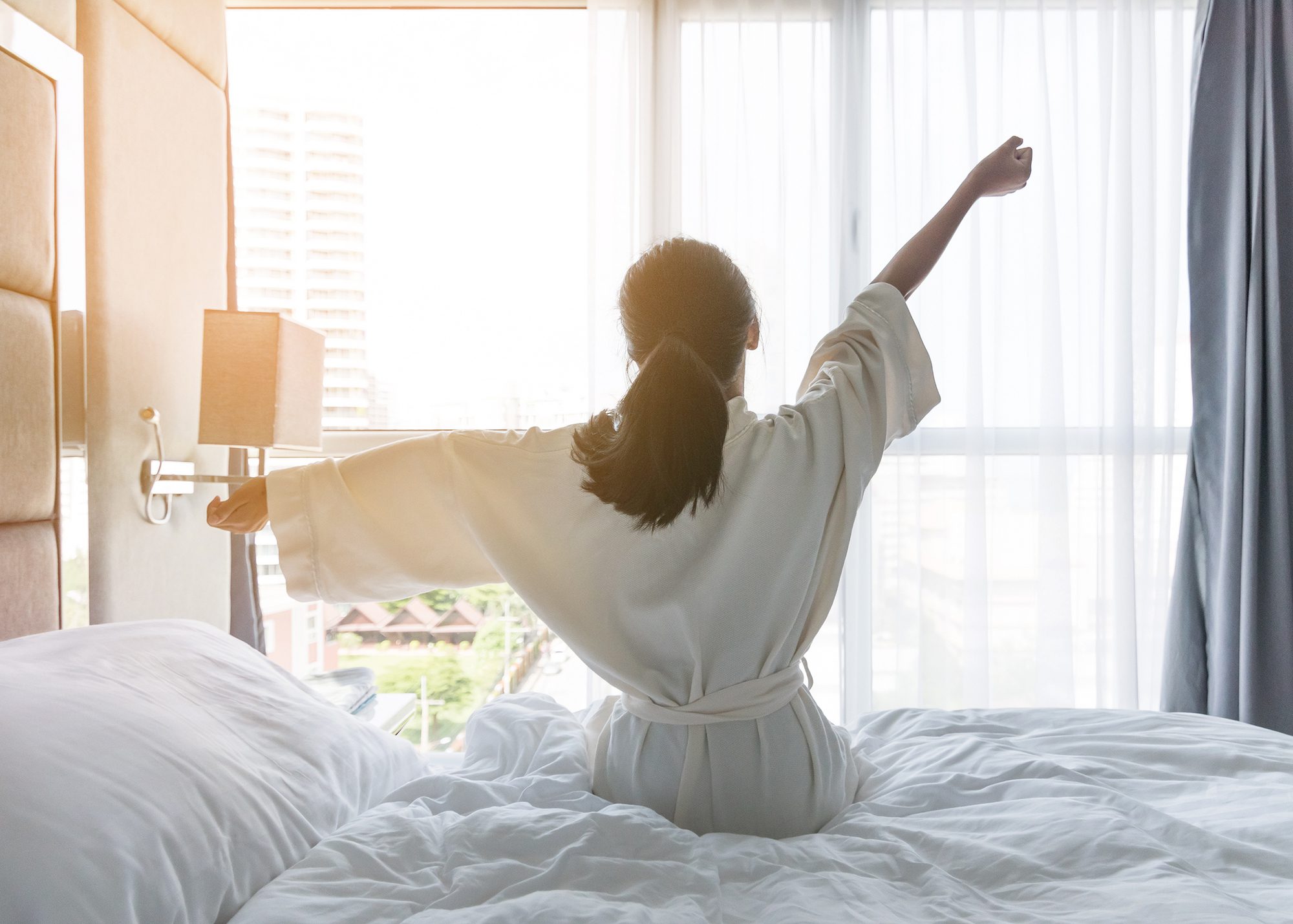 Asian girl woman waking up in the morning taking a rest relaxing in hotel room