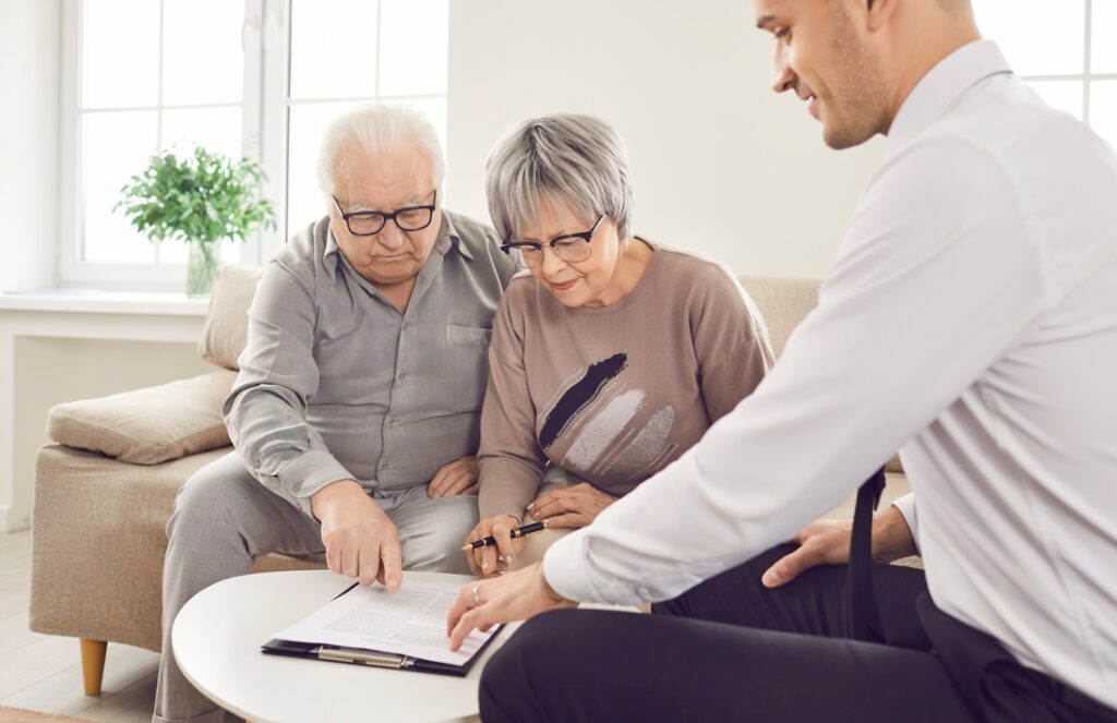 Senior pair and young consultant providing care, giving expert advice, signing documents help.